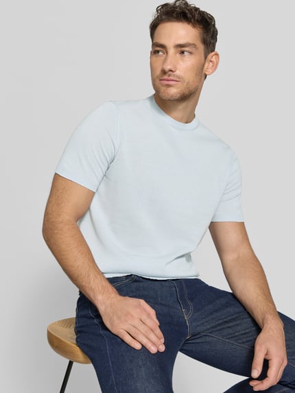 Männermodel trägt Strickshirt mit Rundhalsausschnitt von MARKUP, hellblau, glatte Textur, Regular Fit, Nahaufnahme Oberkörper.