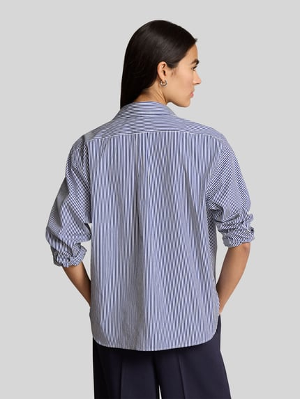 Frauenmodel trägt Slim Fit Hemdbluse aus reiner Baumwolle von Polo Ralph Lauren, Optik: gestreift, Logo-Detail, Ganzkörperansicht Rückansicht.