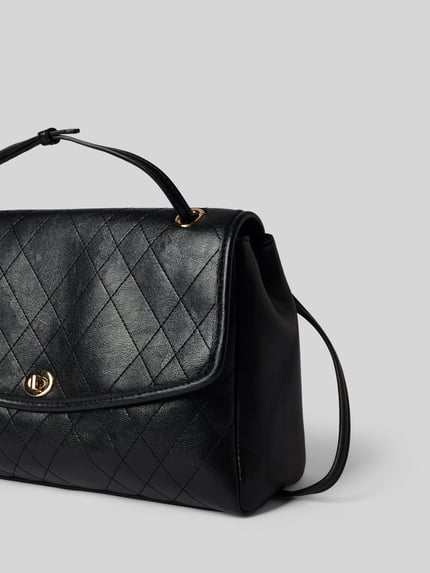 Produktfoto, schwarze Handtasche mit Schulterriemen Modell 'Charlie' von MANGO mit Steppnähten, Überschlag und goldfarbenem Verschluss, leicht strukturierte Oberfläche, neutraler Hintergrund.