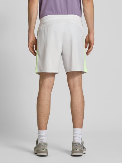 Mężczyzna nosi Shorts mit elastischem Bund und Logo od New Balance, krój regular fit, białe z zielonym akcentem, widok całej sylwetki z tyłu.