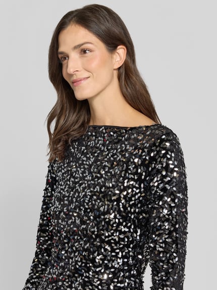 Frauenmodel trägt Paillettenkleid mit U-Boot-Ausschnitt von VERO MODA, glänzende schwarze Struktur, langarm, Nahaufnahme Oberkörper.