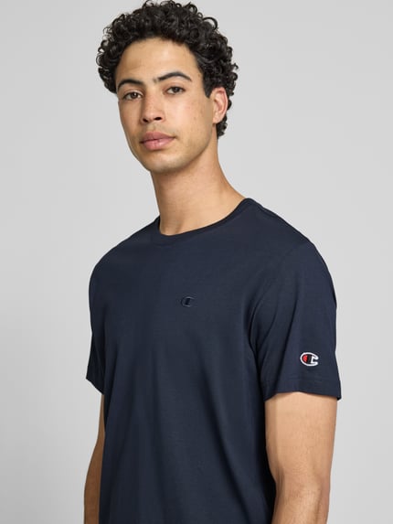Mannermodel draagt T-shirt met Label-Stitchings en ronde hals van CHAMPION in donkerblauw, puur katoen, regular fit, ruglengte maat M 66 cm, Nahaufnahme bovenlichaam.