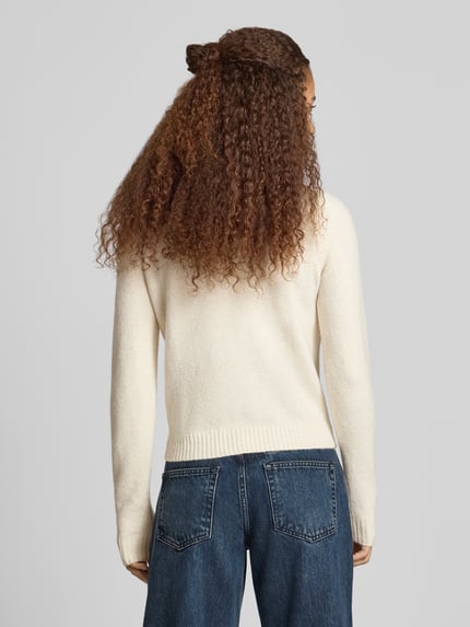 Kobiece model prezentuje Slim Fit Strickpullover aus elastischem Material-Mix von REVIEW, kremowy kolor, prążkowane wykończenia, Wyhaftowany motyw, elastyczna mieszanka materiałów, krój slim fit, długość tyłu w rozmiarze S: 51 cm, długość rękawów w rozmiarze S: 61 cm, widok całej sylwetki od tyłu.