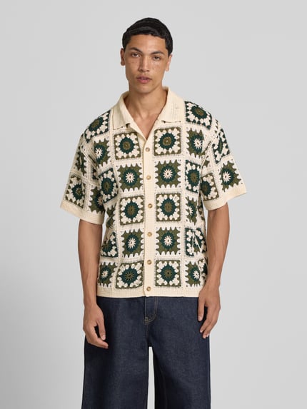 Männermodel trägt Regular Fit Freizeithemd im Allover-Look Modell 'FABIAN' von Redefined Rebel mit Polokragen und Knopfleiste, Ganzkörperansicht von vorne. Rückenlänge bei Größe M: 70 cm, Schulterbreite bei Größe M: 43 cm, Ärmellänge bei Größe M: 28 cm. Farbe creme mit grünem Muster, strukturierte, gehäkelte Optik.