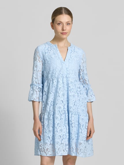 Frauenmodel trägt Loose Fit Spitzenkleid aus Baumwoll-Mix Modell 'HONEY' von Vero Moda in Hellblau, Spitzen-Muster, knielang, V-Ausschnitt, 3/4-Arm mit Glockenärmel, Optik: Unifarben, Materialverarbeitung: Spitze, Nahaufnahme Oberkörper.