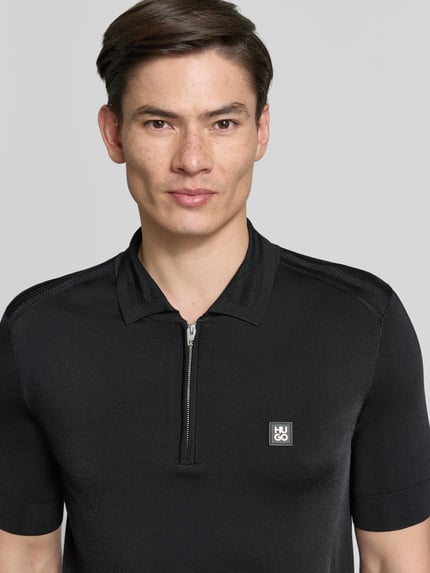 Męski model nosi Regular Fit Poloshirt aus Viskose-Mix model 'SAYFONG-4' od HUGO, efekt: jednolity kolor, naszywka z logo, kołnierzyk polo, listwa guzikowa, krótki rękaw, prążkowane wykończenia, dżersej, mieszanka wiskozy, zbliżenie na górną część ciała