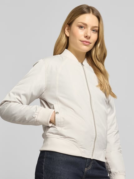 Vrouwenmodel draagt licht beige regular fit jack met opstaande kraag, steekzakken, ritssluiting van model 'Zaymi' van CARS JEANS, elastische boorden, ruglengte maat S 61 cm, schouderbreedte 41 cm, borstwijdte 39 cm, mouwlengte 60 cm. Nahaufnahme bovenlichaam.