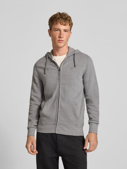 Männermodel trägt Regular Fit Sweatjacke aus Baumwoll-Mix mit Label-Detail von Superdry, grau, Kängurutasche, elastische Abschlüsse, Ganzkörperansicht von vorne. Rückenlänge und Ärmellänge 65 cm, Kapuze mit Tunnelzug, Kontext: Herren Sweatjacke von Superdry.