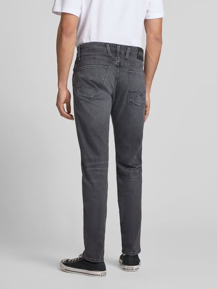Męski model nosi szare jeansy Slim Fit Jeans im 5-Pocket-Design Modell 'Anbass' od Replay, dopasowany krój, 5 kieszeni, zapięcie na guzik i zamek błyskawiczny, szerokość w rozmiarze 32/32: 43 cm, długość wewnętrzna nogawki: 83 cm, zdjęcie całopostaciowe z tyłu