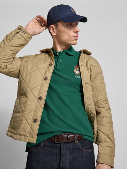 Männermodel trägt Regular Fit Poloshirt aus reiner Baumwolle von Polo Ralph Lauren in uni grün, piqué, label stitching, kurzarm, Nahaufnahme Oberkörper.