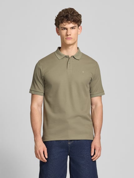 Męski model nosi Regular Fit Poloshirt mit Strukturmuster Modell 'AUSTIN' von Jack & Jones, kolor khaki, materiał mieszany z bawełną, guzikowana plisa, stitching, długość tyłu w rozmiarze M: 69 cm, krój regular fit, widok całej sylwetki z przodu.