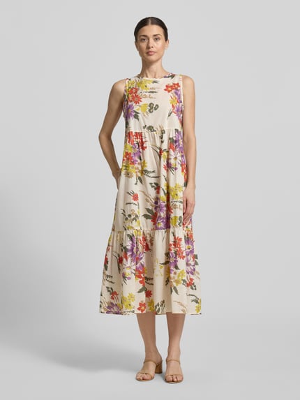 Frauenmodel trägt Midikleid mit Rundhalsausschnitt Modell 'TABARIN' von EMME aus Reine Baumwolle, Loose-Fit, Volantsaum, florales Muster, Ganzkörperansicht von vorne.