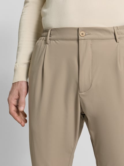 Männermodel trägt Slim Fit Hose mit Paspeltaschen am Gesäß von CRUNA in Beige, Material-Mix mit Stretch-Anteil, Eingrifftaschen, Nahaufnahme Oberkörper.
