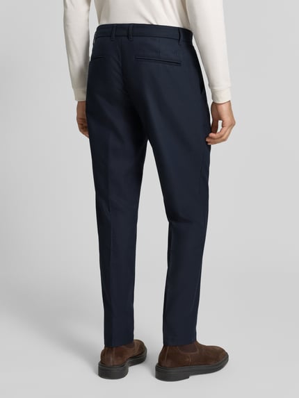 Männermodel trägt Regular Fit Anzughose mit Bügelfalten von Les Deux, dunkelblauer Material-Mix, Bund und Gesäßtaschen, Ganzkörperansicht Rückansicht. Kontext: Herren Anzughose von Les Deux, Material-Mix mit Woll-Anteil, Regular Fit, Bügelfalten, Gesäßtaschen, Bundweite bei Größe 32: 44 cm, Innenbeinlänge bei Größe 32: 78 cm.