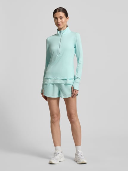 Frauenmodel trägt Longsleeve mit Stehkragen und Reißverschluss von Under Armour aus Material-Mix mit Stretch-Anteil, Regular-Fit, Logo, Rückenlänge bei Größe S: 59 cm, hellblau, Ganzkörperansicht von vorne.