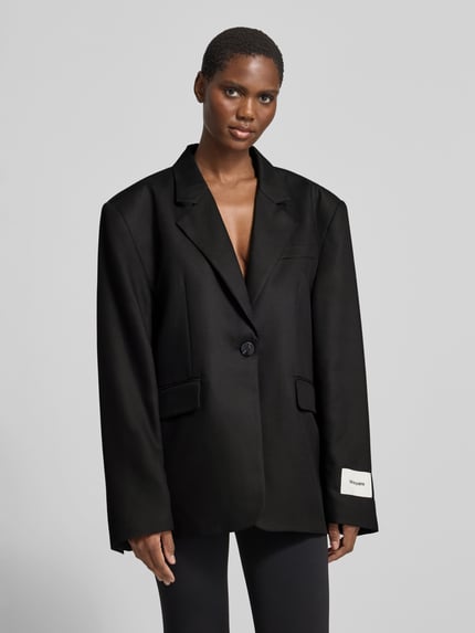 Frauenmodel trägt schwarzen Regular Fit Longblazer mit Label-Detail von black palms, unifarbene Optik, Reverskragen, Pattentaschen, 1-Knopf-Verschluss, langarm, Ganzkörperansicht von vorne.