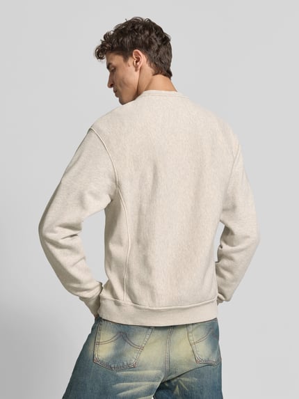 Männermodel trägt Sweatshirt mit Label-Prägung von KENZO in Beige, lockere Passform, elastische Abschlüsse, Rückenansicht, Ganzkörperansicht Rückansicht.