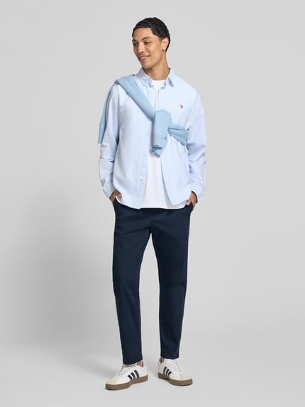 Männermodel trägt Straight Fit Hose aus katoenmix van REVIEW in navy met steekzakken en achterzakken, knoop- en ritssluiting, bandwijdte maat M 42 cm, binnenbeenlengte maat M 69 cm, geheel vooraanzicht.