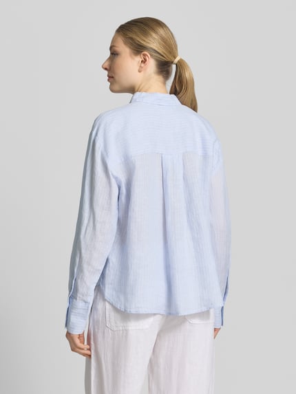 Männermodel trägt Regular Fit Hemdbluse mt Knopfleiste von Christian Berg Woman Selection, jasny niebieski, półprzezroczysty, długi rękaw, krój regular fit, pełna długość guzików, kołnierzyk koszulowy, widok całej sylwetki z tyłu.