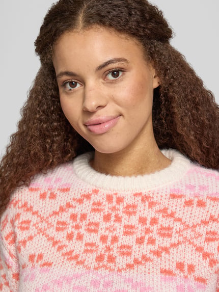 Frauenmodel trägt Pullover mit Jacquardstruktur Modell 'ONLCARO' von ONLY, mehrfarbiges geometrisches Strickmuster, Nahaufnahme Oberkörper.