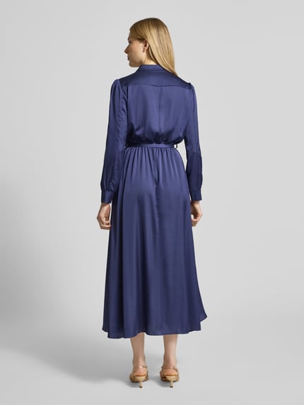 Vrouwenmodel draagt Abendkleid aus Satin met V-Ausschnitt und Gürtel van Rinascimento, donkerblauw, A-lijn, midilengte, glanzende satijnstructuur, knopenrij, riem, ruglengte 131 cm, borstwijdte 46 cm, mouwlengte 60 cm, Ganzkörperansicht Rückansicht.