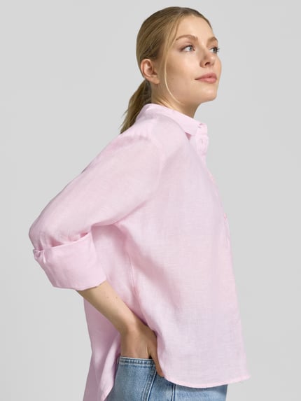 Frauenmodel trägt Regular Fit Hemdbluse aus reinen Leinen von Christian Berg Woman Selection in zartem Rosa mit Hemdblusenkragen und Knopfleiste, langärmliges Design, reine Leinenstruktur mit leichter Transparenz, Nahaufnahme Oberkörper seitlich.