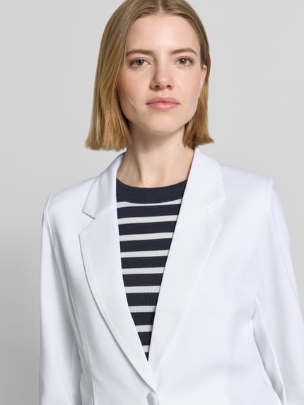 Männermodel trägt Blazer mit Viskose-Anteil Modell 'Nanni' von FREE/QUENT, biały kolor, taliowany krój, kołnierz z klapami, 2-guzikowe zapięcie, elastyczna mieszanka materiałów, szerokość w rozmiarze S: 46 cm, długość tyłu: 58 cm, długość rękawa: 57 cm, zbliżenie na górną część ciała.
