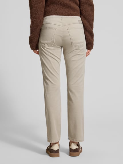 Frauenmodel trägt Relaxed Fit Stoffhose mit elastischem Bund Modell 'Pamina' von Raphaela By Brax, beigefarbener Baumwoll-Mix, sichtbare Taschen, strukturierte Oberfläche, Ganzkörperansicht Rückansicht.