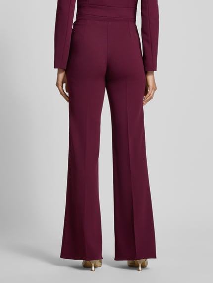 Frauenmodel trägt Flared Fit Stoffhose mit Bügelfalten von Rinascimento in dunklem Rot, elastischer Bund, glatte Textur, Ganzkörperansicht Rückansicht.