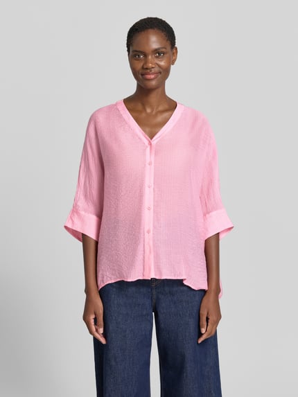 Modelka nosi Relaxed Fit Bluse aus Viskose-Mix mit 3/4-Arm von comma, różowa bluzka, dekolt w serek, listwa guzikowa, długość tyłu 62 cm, długość rękawa 18 cm, mieszanka wiskozy, krój relaxed fit, widok całej sylwetki z przodu.