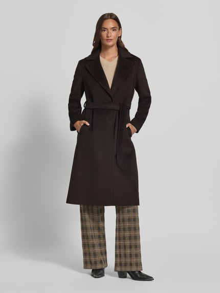 Frauenmodel trägt Mantel aus Woll-Mix mit Bindegürtel von ICONS Cinzia Rocca in Dunkelbraun, taillierter Schnitt, Reverskragen, Knopfverschluss, glatte Textur, braune Hose mit Karomuster, lange Ärmel, Ganzkörperansicht von vorne. Rückenlänge 110 cm, Schulterbreite 42 cm, Brustweite 47 cm, Ärmellänge 61 cm.