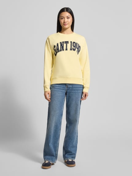 Frauenmodel trägt Sweatshirt mit Label-Print und Rundhalsausschnitt von Gant in Gelb, Relaxed-Fit, Reine Baumwolle, Ganzkörperansicht von vorne.