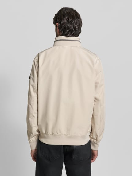 Männermodel trägt Regular Fit Jacke mit Kapuze von NAUTGÅRD in Beige, glatte Oberfläche, Stehkragen, Rückenansicht, Ganzkörperansicht.