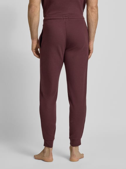 Männermodel trägt Relaxed Fit Pyjama-Hose aus Baumwoll-Mix Modell 'AUSTIN PANTS' von HUGO, Unifarben, Waffel-Struktur, Ganzkörperansicht Rückansicht.