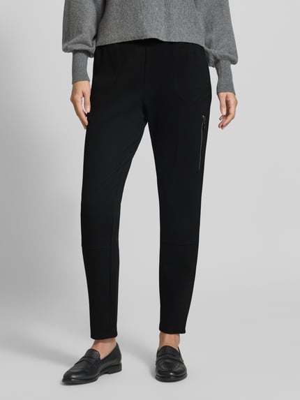 Frauenmodel trägt Slim Fit Sweatpants aus Viskose-Mix von monari in Schwarz, elastischer Bund mit Tunnelzug, verkürzte Passform, Nahaufnahme Unterkörper.