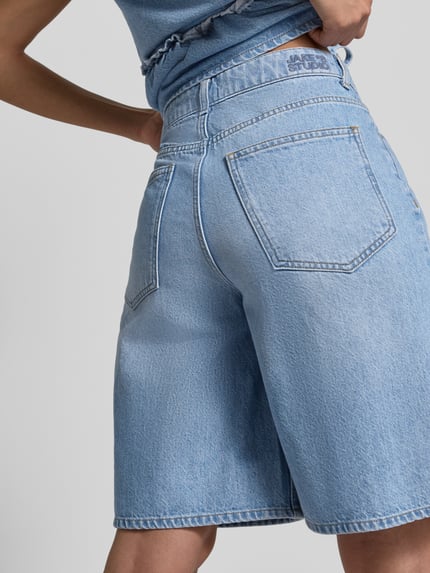 Vrouwenmodel draagt Bermudas in Denim-Optik van JAKE*S STUDIO WOMAN, lichtblauw, losvallend, 5-pocket, detailopname achterkant.