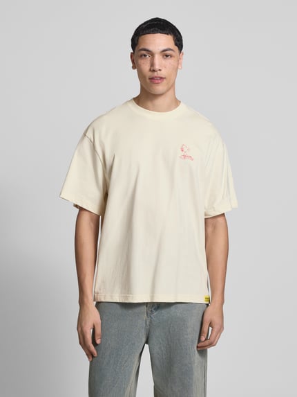 Męski model nosi Regular Fit T-Shirt aus reiner Baumwolle Modell 'PEANUTS' von Only & Sons, kremowy, nadruk Peanuts®, jersey, krótki rękaw, krój regular fit, widok całej sylwetki z przodu.