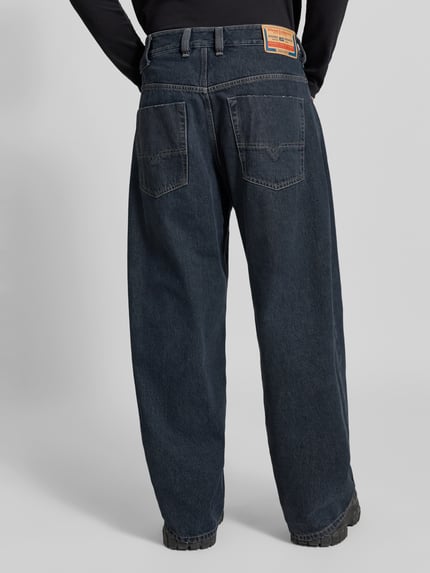 Männermodel trägt Relaxed Fit Jeans aus reiner Baumwolle von Diesel in Dunkelblau, 5-Pocket-Design, Label-Detail, Ganzkörperansicht Rückansicht.