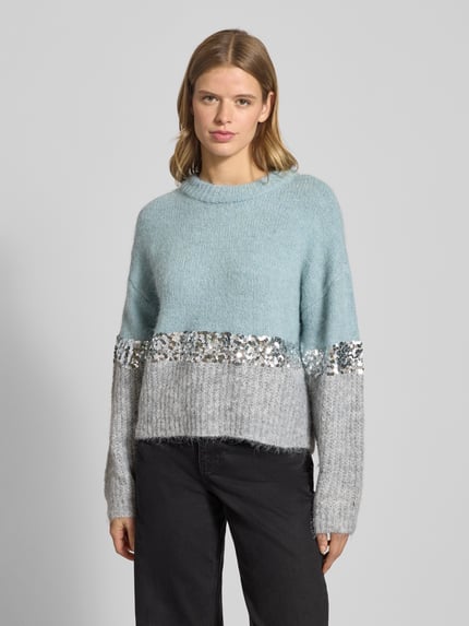 Frauenmodel trägt Relaxed Fit Strickpullover mit Woll-Anteil Modell 'MAINE' von Only in Two-Tone-Optik mit Paillettenbesatz, Rundhals und gerippten Abschlüssen, Strick-Material, Ganzkörperansicht von vorne.