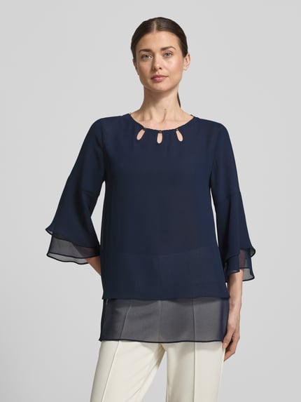 Frauenmodel trägt Regular Fit Blusenshirt aus fließendem Stoff von Vera Mont, dunkelblauer Chiffon, Stufen-Look, 3/4-Arm, Ganzkörperansicht von vorne.