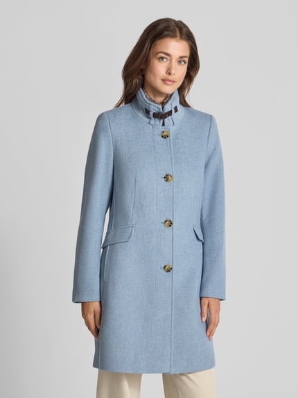 Frauenmodel trägt Mantel mit Kunstfell und Pattentaschen von Christian Berg Woman Selection in Hellblau, Material-Mix, Stehkragen, Knopfleiste, Slim Fit, Pattentaschen, Ganzkörperansicht von vorne.