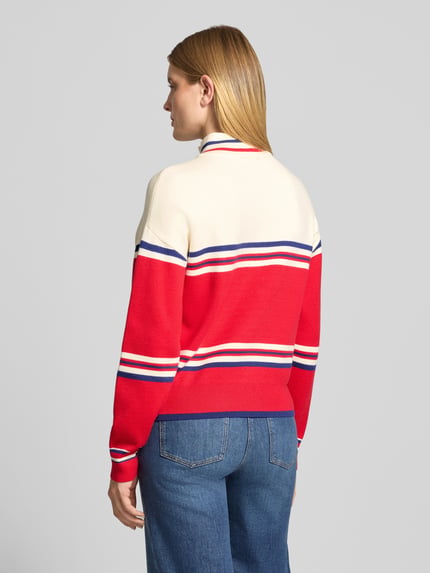 Frauenmodel trägt Troyer mit Après-Schriftzug von JAKE*S WOMAN CASUAL, gestreifter Strick in Rot, Creme und Blau, Ganzkörperansicht Rückansicht.