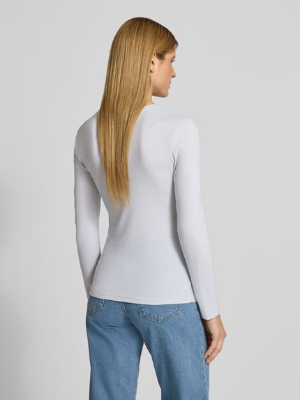 Vrouwenmodel draagt Slim Fit Langarmshirt aus Lyocell-Mix van Marc O'Polo, look: effen, pasvorm: slim fit, ronde hals, lange mouw, materiaalverwerking: rib, materiaal: lyocellmix, geheel wit, textuur fijn geribbeld, Ganzkörperansicht Rückansicht.