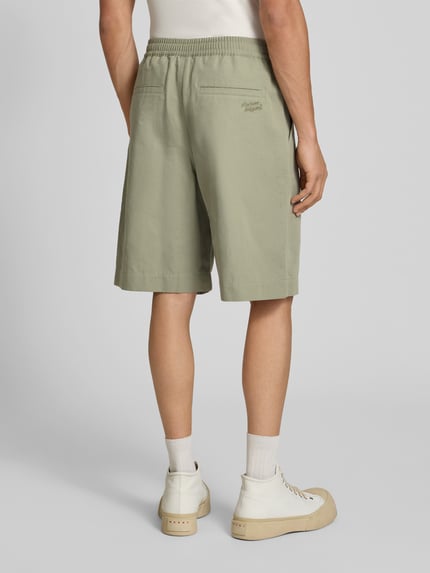 Männermodel trägt Shorts aus katoenmix van MAISON KITSUNÉ in regular fit met elastische band, steekzakken, knielengte, bandwijdte maat M 41 cm, binnenbeenlengte 24 cm, lichtgroene kleur, gladde textuur. Ganzkörperansicht Rückansicht.