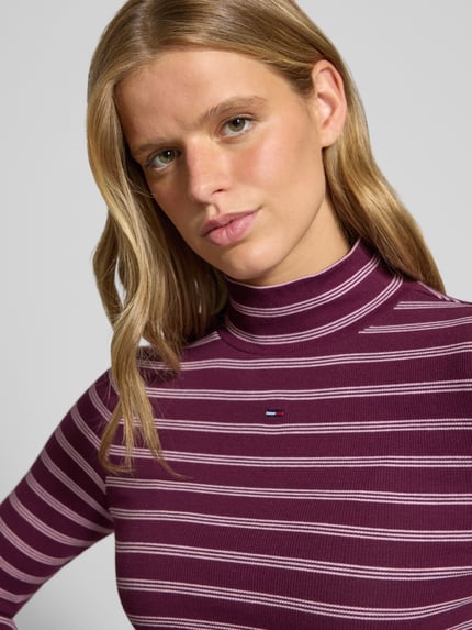 Frauenmodel trägt Slim Fit Langarmshirt aus Baumwoll-Mix von Tommy Jeans in Lila mit weißen Streifen, Nahaufnahme Oberkörper, Damen Langarmshirt von Tommy Jeans