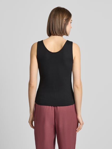 Modelka kobieca nosi Slim Fit Tank Top aus Baumwoll-Mix Modell 'SIMPLE' od Only, czarny, gładki, krój slim fit, szerokie ramiączka, dekolt U, delikatny prążek, widok całej sylwetki z tyłu.