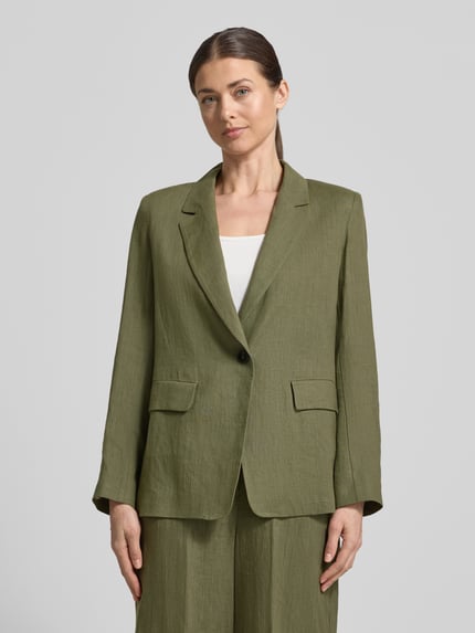 Modelka kobieca nosi Regular Fit Blazer aus Leinen Modell 'VINCITA' od Emme, oliwkowy len, kołnierz z połami, zapięcie na guzik, kieszenie z patką, długość tyłu w rozmiarze 36: 68 cm, szerokość w rozmiarze 36: 48 cm, długość rękawów w rozmiarze 36: 64 cm, widok całej sylwetki z przodu.