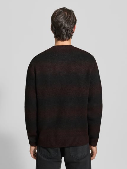 Męski model nosi Strickpullover mit Rundhalsausschnitt od Jack & Jones Premium, luźny krój, melanż czerni i bordo, widok z tyłu, długość 68 cm.