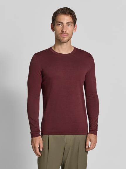Männermodel trägt Regular Fit Longsleeve aus reiner Baumwolle Modell 'Irmino' von DRYKORN in Burgunderrot, Strick-Optik, Ganzkörperansicht von vorne.