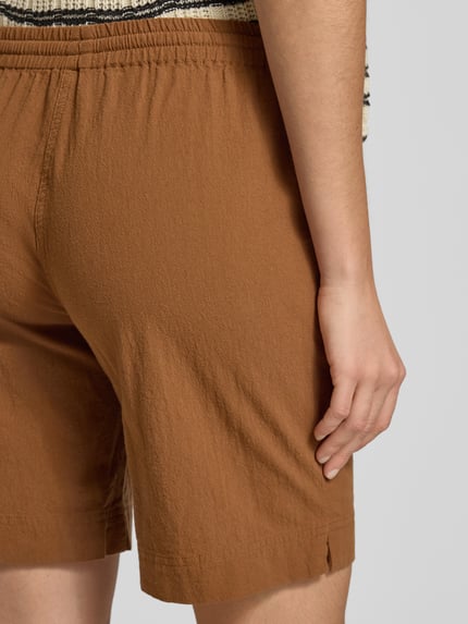 Frauenmodel trägt Shorts mit elastischem Bund Modell 'Cissie' von Soyaconcept, reine Baumwolle in Braun, Strukturstoff, Ganzkörperansicht Rückansicht.